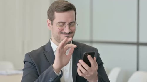 Excited Man Using Phone in Modern Office