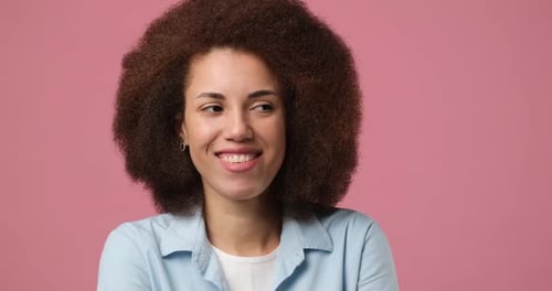 Jovem mulher afro-americana gesticulando o dedo nos lábios sorrindo mostrando um sinal secreto de Keep Silence Hush