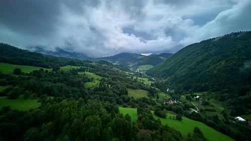 Hyperlapse aus der Luft von Green Valley mit bewaldeten Hügeln und Dramatisch bewölktem Himmel vor dem Sturm