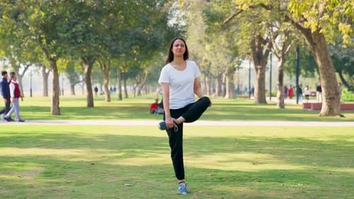 Woman Balancing and Stretching in Sunny Park