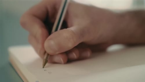 Close-up of a male hand-writing a to-do list in a notebook with a pen. Lifestyle and work-from-home