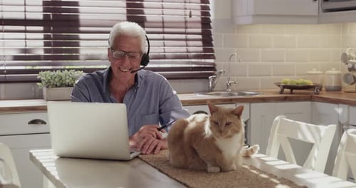 Smiling Man Using Laptop with Cat at Home