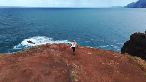 Woman Walking on Cliff Edge Overlooking Ocean View