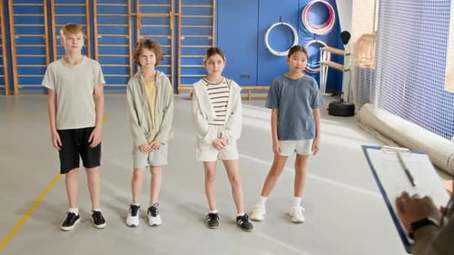 Children in Row in Gym and Listening to Black Male Teacher Giving Instructions