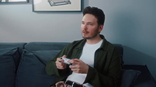 Man Relaxes on Sofa Playing Video Games