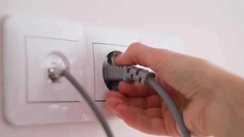 Hand Unplugging Power Cord from Outlet