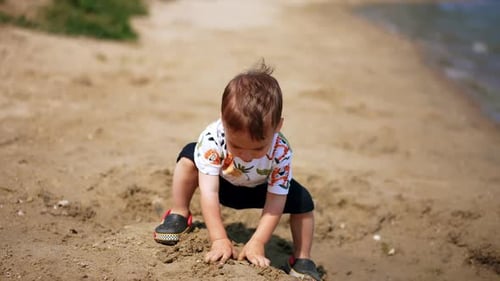 Child Plays with Sand on the Beach