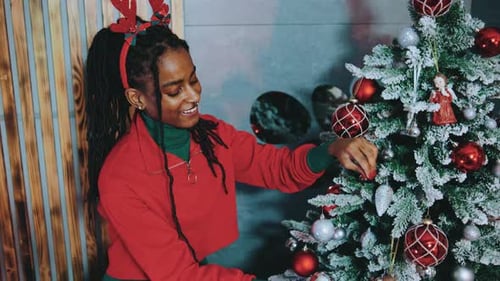 Smiling Woman Decorating Christmas Tree with Ornaments