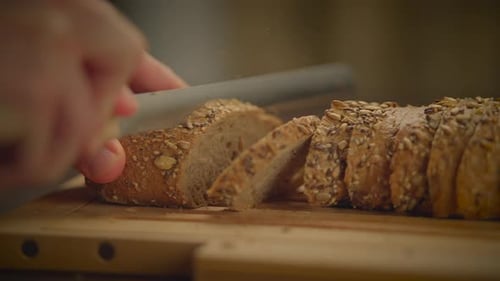 Slicing a Loaf of Multigrain Bread on Board