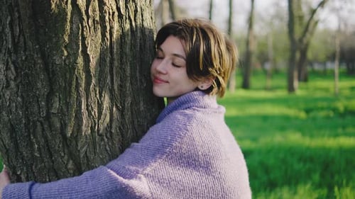 Woman Hugs Tree in Park During Daylight Showing Connection to Nature and Appreciation for the