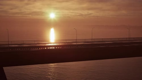 Sun Setting Over Ocean With Bridge in Foreground