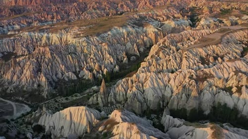Cappadocia landscape with tuff stone formations after sunrise, tilt down aerial