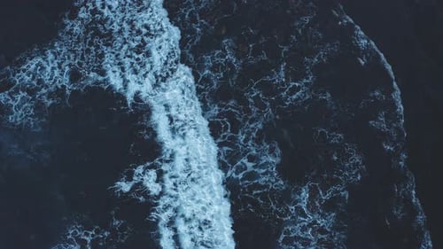 Vista aérea de arriba hacia abajo de olas gigantes de color azul oscuro que chocan y hacen espuma en la playa. Ola poderosa.