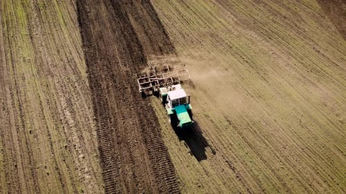 Aerial View of Tractor Tilling Brown Field