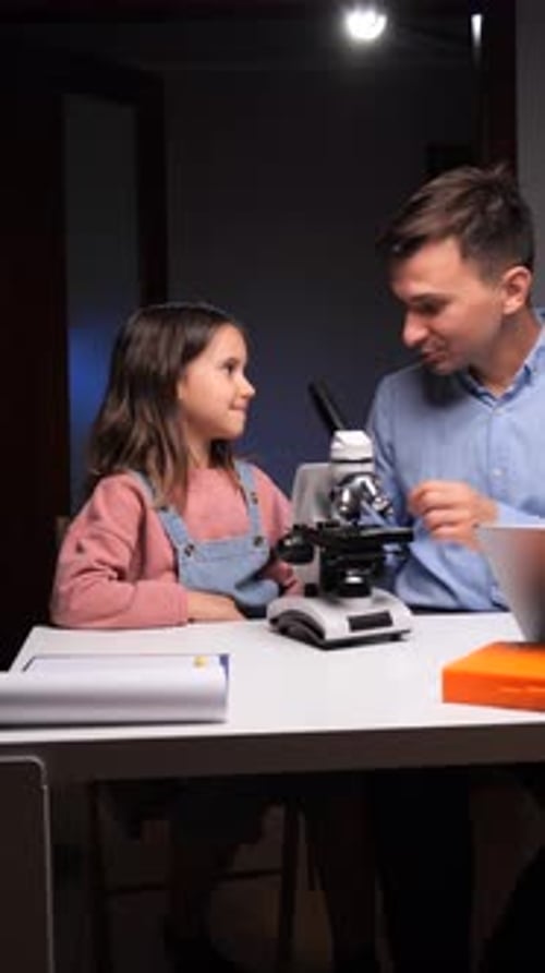 Girl and Man Doing Science with Microscope Indoors