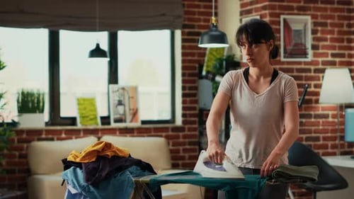 Woman Ironing Clothes at Home, Man in Background