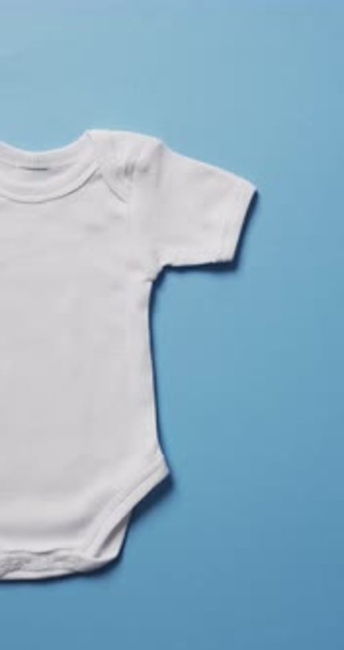 Vertical video of white baby grow with copy space on blue background