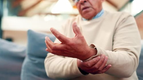 Senior Man Massaging Sore Wrist Joint at Home