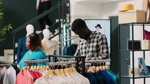 Man Browsing Clothing Rack in Modern Clothing Store