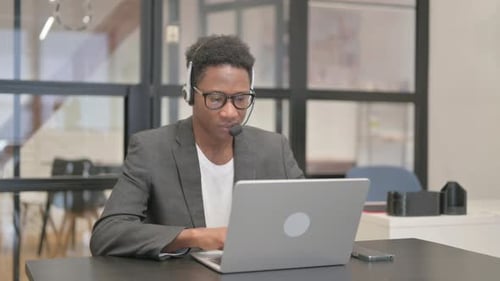 Young Adult Working on Laptop With Headset