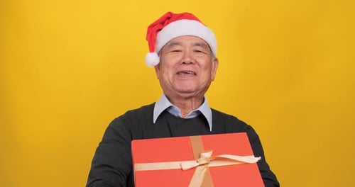 Senior Man Holding a Christmas Present and Smiling