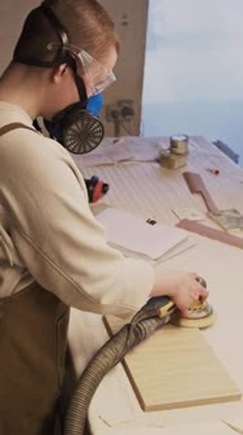 Adult Sanding Wood with Powered Sander in Workshop
