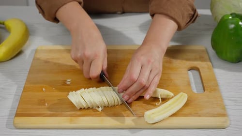 Banana Being Sliced on a Cutting Board