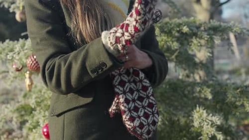 Frau trägt rote gestrickte gemusterte Fäustlinge an einem kalten, sonnigen Weihnachtstag
