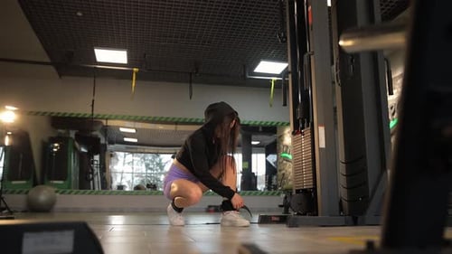 Woman Building Thigh Muscles with Gym Equipment on Hardwood Flooring