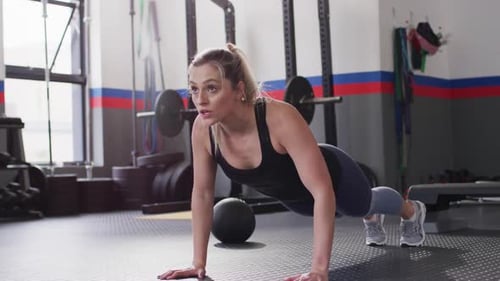 Video of determined caucasian woman doing push ups working out at a gym