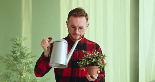 Man Watering Plant in an Indoor Space