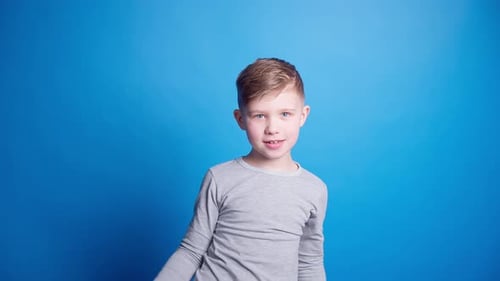 hübscher blauäugiger Junge mit rotem Hut auf blauem Hintergrund lacht