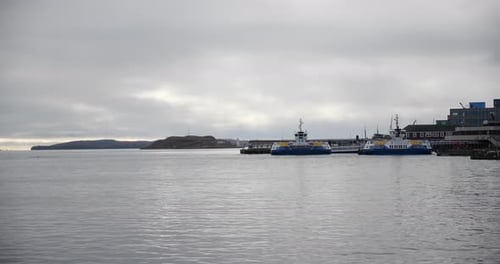 Passenger ferries arriving and departing from the terminal on the harbour with island and lighthouse