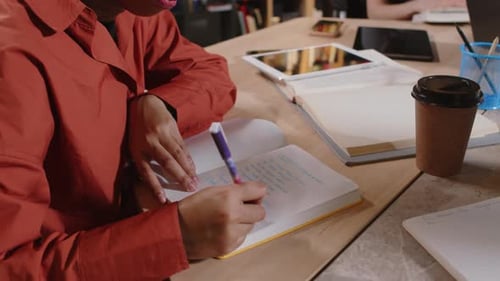 Muslimische Studentin im Hijab macht sich Notizen am Schreibtisch in der College-Bibliothek