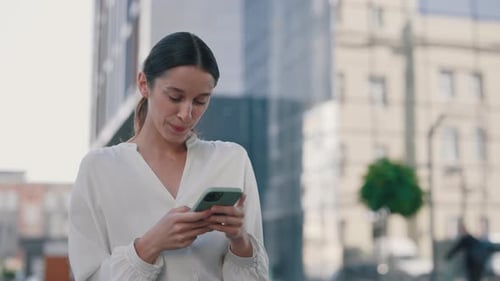 Attractive Smiling Businesswoman Using Mobile Phone App While Standing in an Urban Area She Is