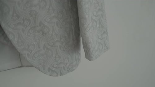 Nahaufnahme eines aufwendig gemusterten Hochzeitsanzugärmels aus leichtem Stoff mit detailreicher Stickerei