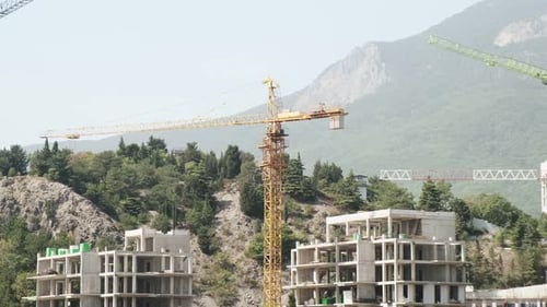 Close-up Construction cranes with new buildings under construction against the backdrop of a mountai