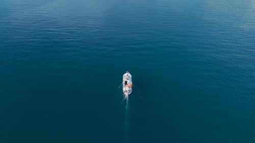 Vídeo aéreo de un barco de pesca en el agua con vistas panorámicas urbanas y cielos azules claros capturados