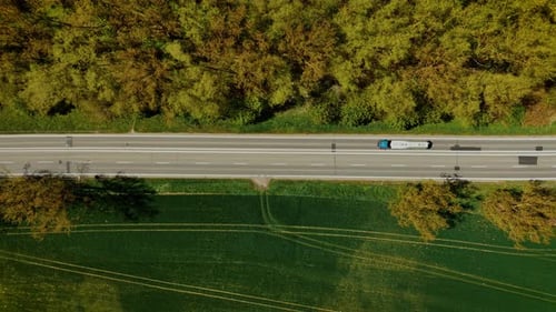 Tanker Truck Driving Along Empty Road Between Green Field and Forest Fuel Lorry Moving on