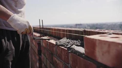 bricklayer lays red brick, masonry wall