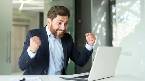 Excited Businessman Celebrating Success at Office Desk