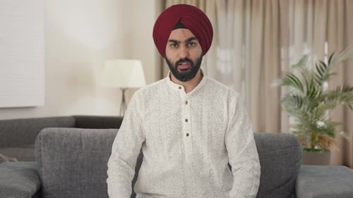 Young Adult in Turban Talking on a Gray Couch