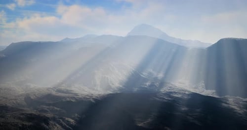 Light Rays Illuminating Mountainous Landscape Under Cloudy Sky