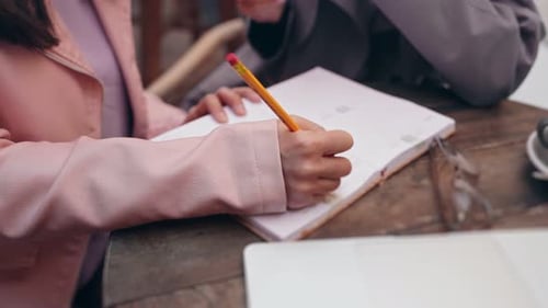 Closeup of Woman Writing in Agenda at Cafe Meeting