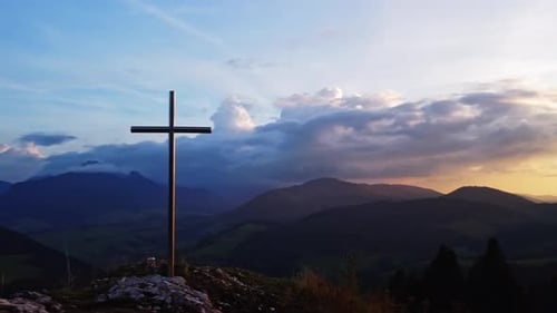 Aerial View of a Religious Christian Steel Cross on a Hill in the Mountainous Countryside in Sunset