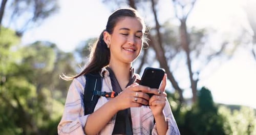 Smiling Woman Using Smartphone in Sunny Forest Setting