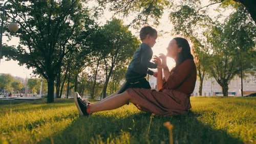 Brother and older sister play in the park in the spring at sunset. Happy family. Slow motion