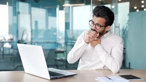 Bearded Man Coughing While Using Laptop in Office