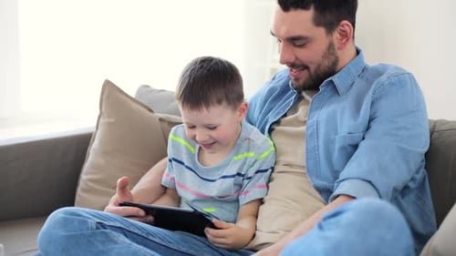 Father and Son Using Tablet on Sofa