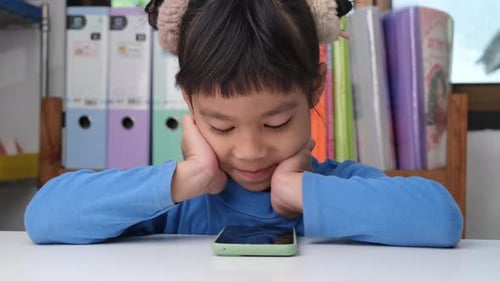 Girl Interacting with Smartphone at a Table